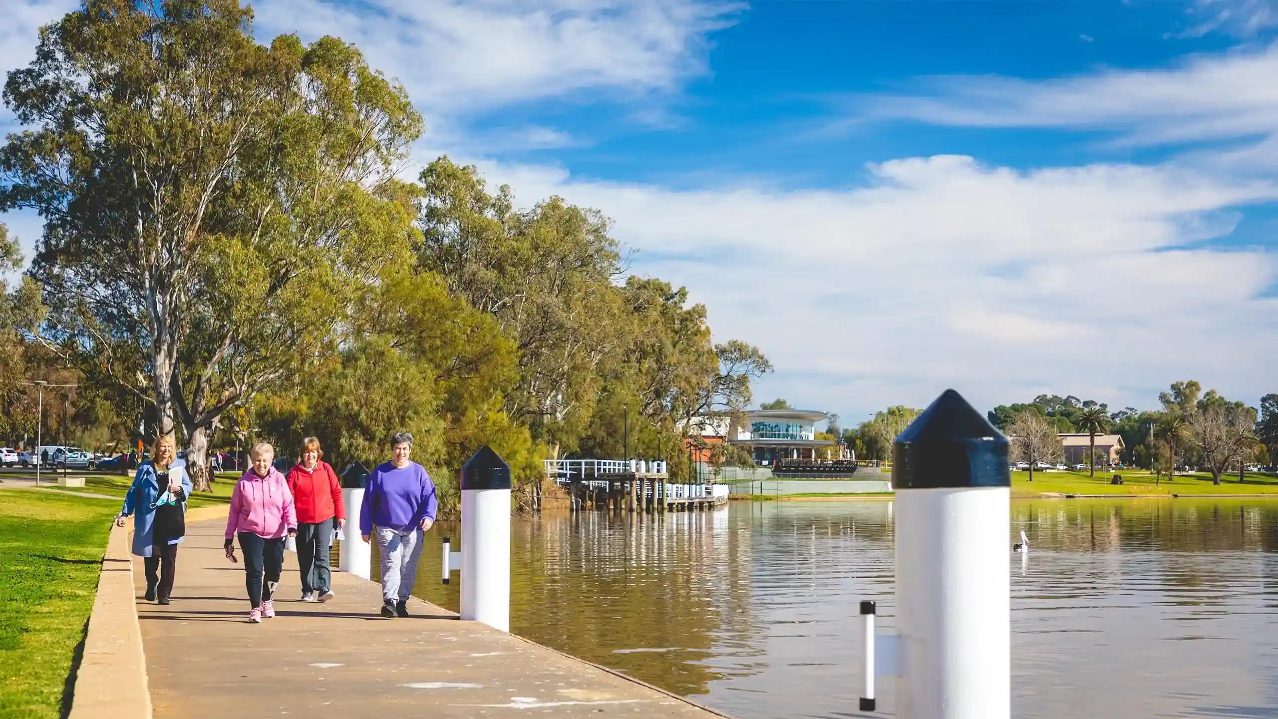 people walking next to a river in the sunshine