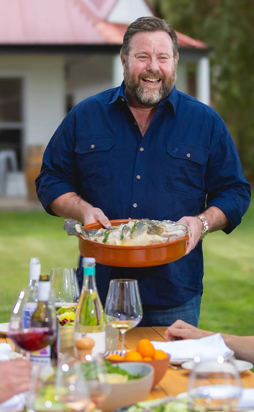 A happy man holding a dish of food in his hand.