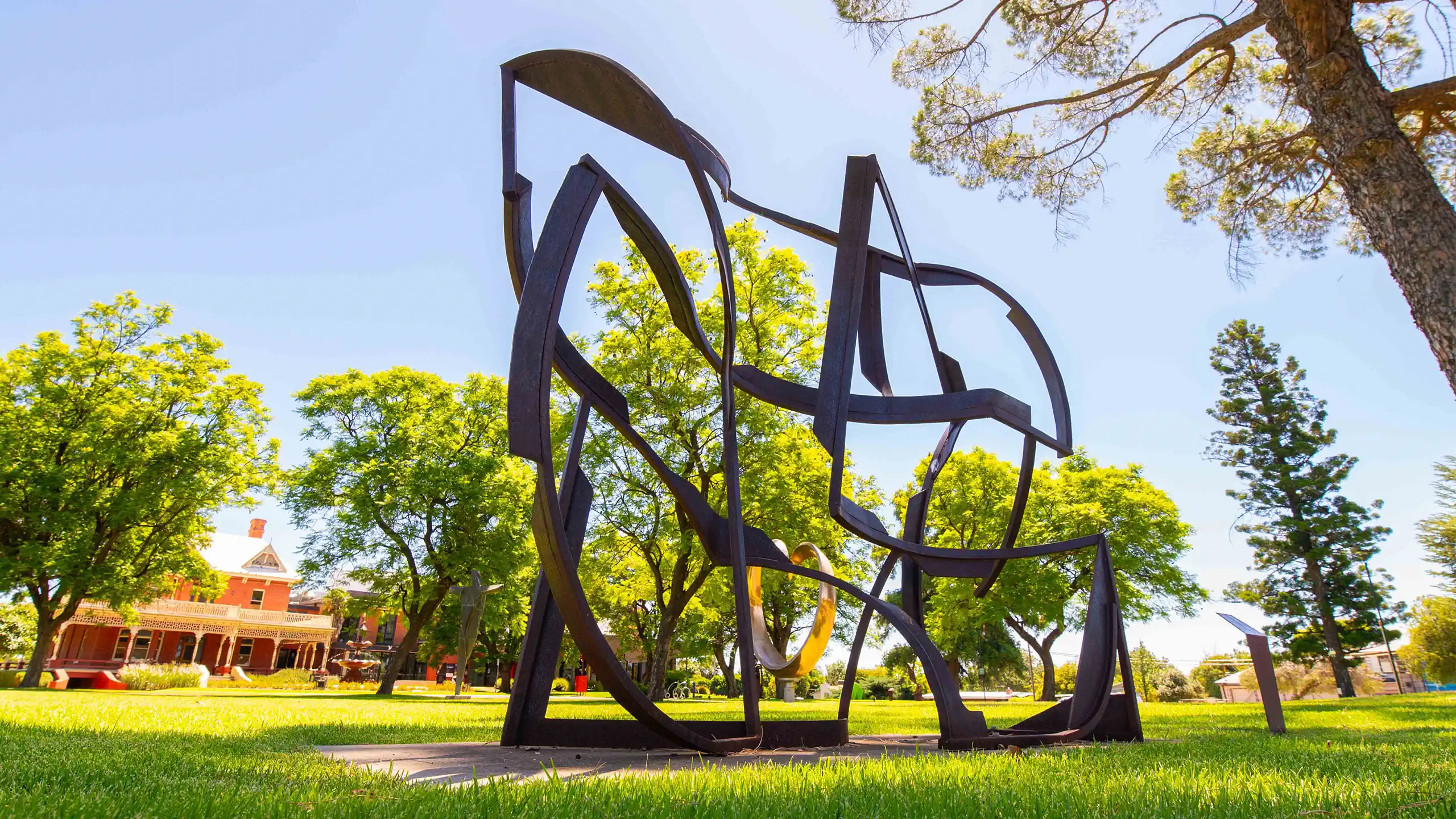 Sculptures in a park with buildings visible in the background.