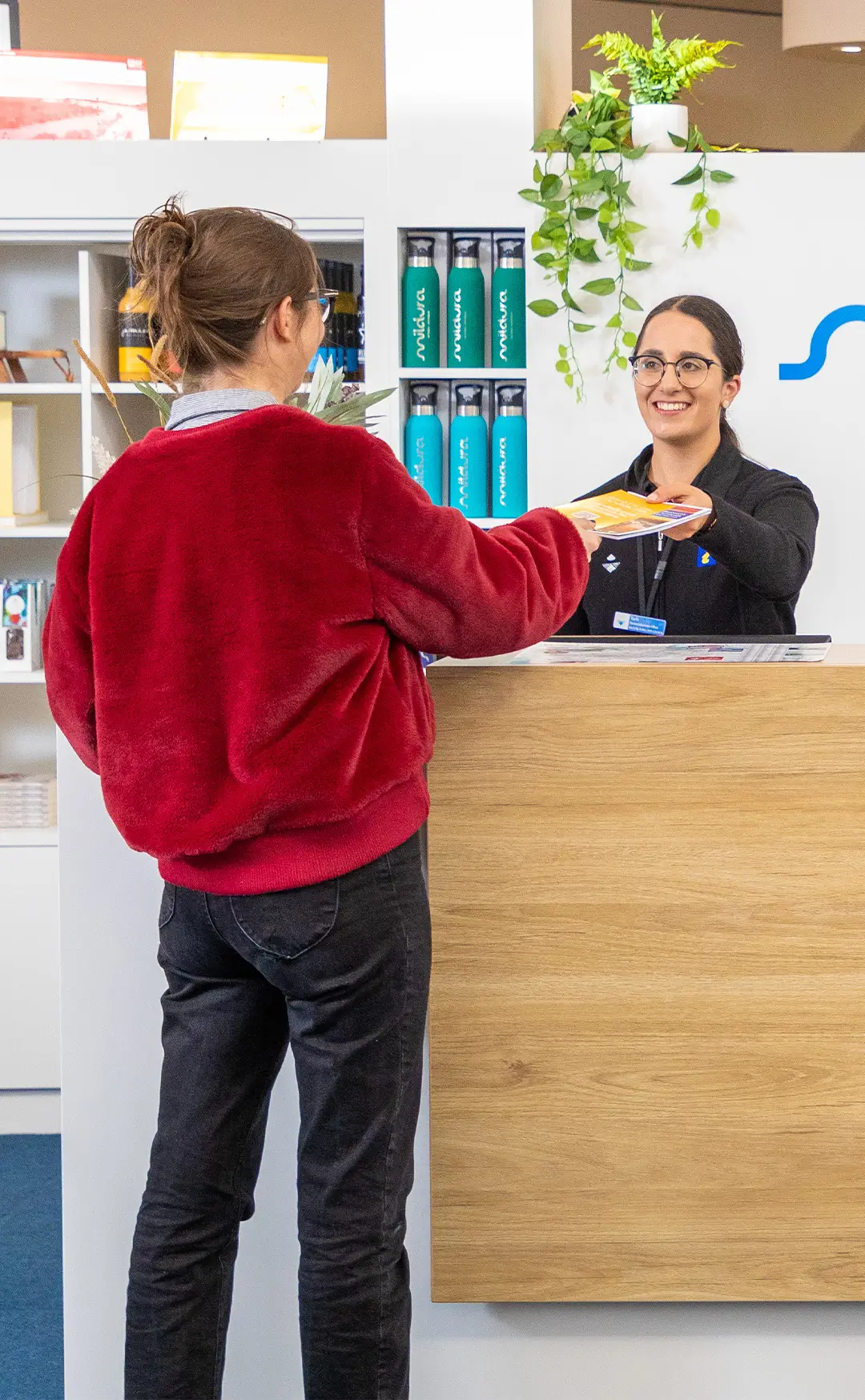 A staff member at the helpdesk handing an information pack to a visitor at the Mildura Visitor Information Centre.